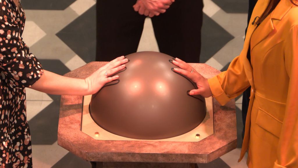 close up of two hands touching large sphere 